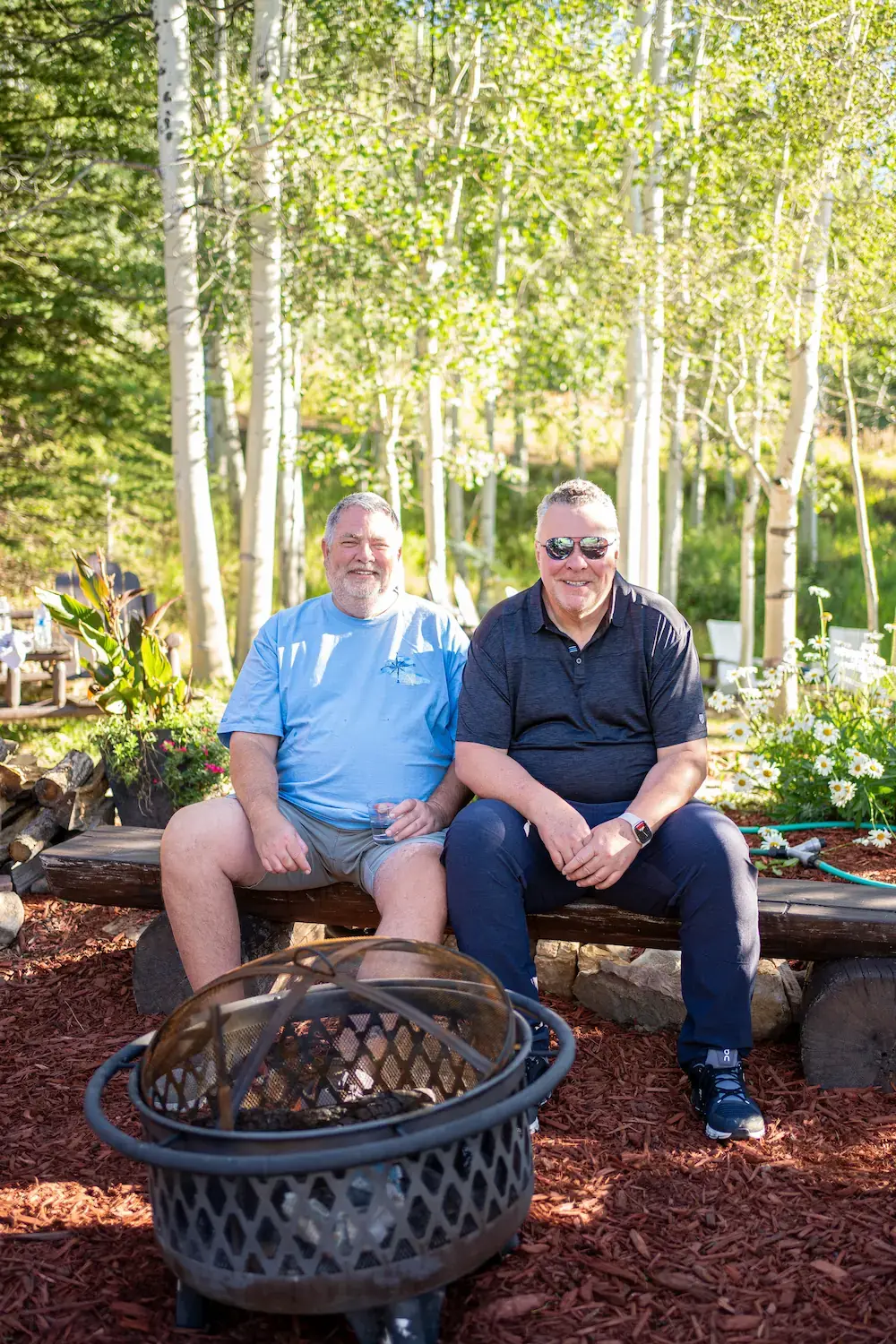 Two ETC team members sitting on a log bench smiling for a photo