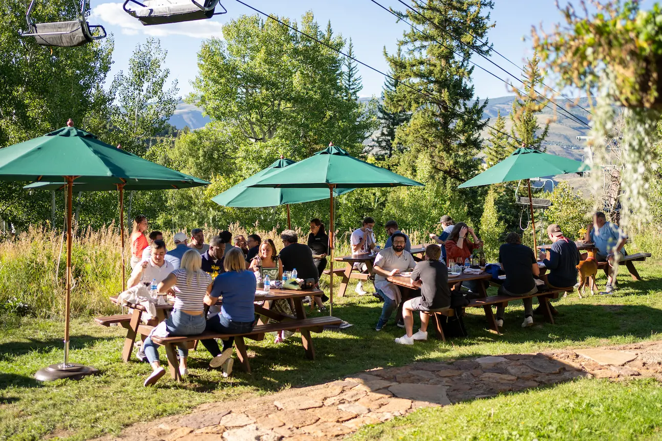 The entire ETC team eating dinner on a series of picnic benches in the mountains